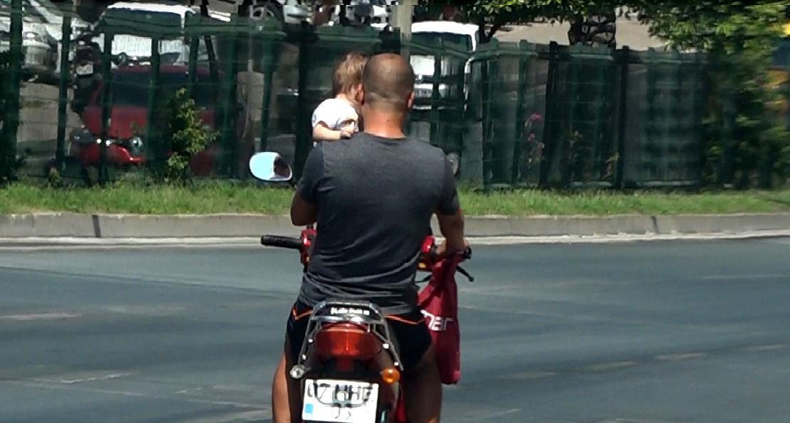 Bir koluyla bebeğini taşıdı diğeriyle motosiklet sürdü