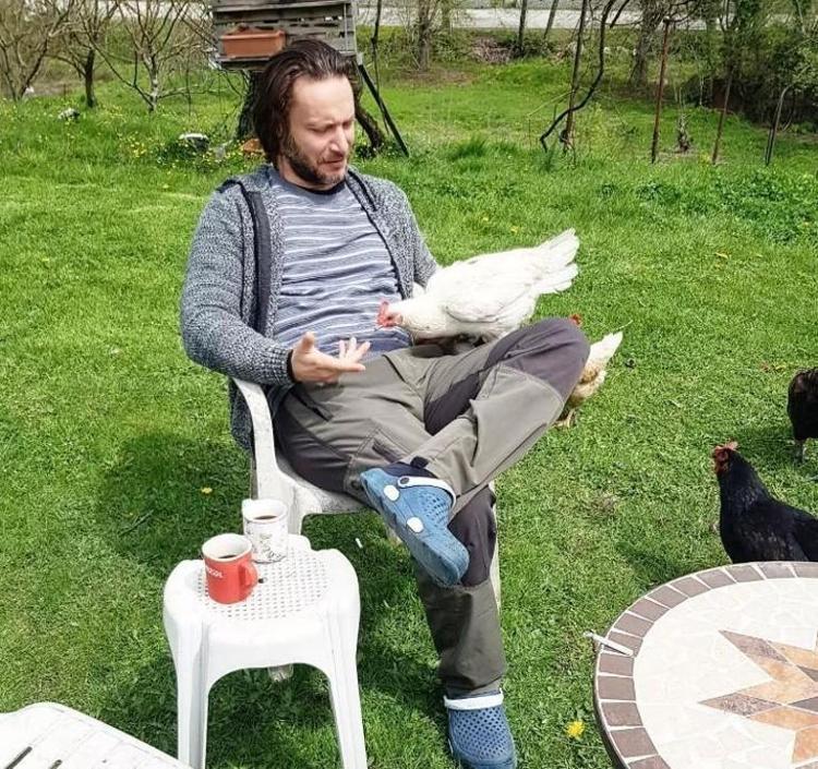BAHÇESİNDE TAVUK BESLİYOR